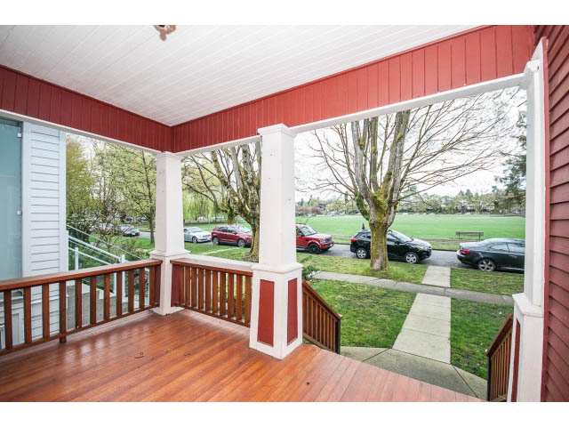 Spacious porch with red siding and wooden deck, overlooking greenery and parked cars. - 769 West 20th Ave, Vancouver West Side