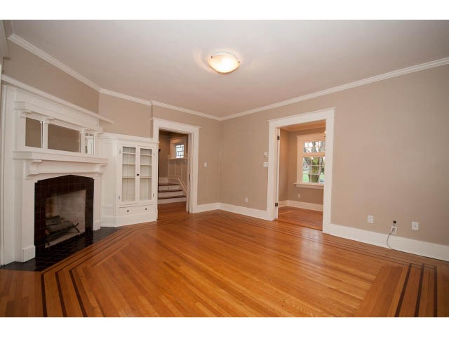 Spacious living room with hardwood floors and fireplace, leading to a kitchen area. - 769 West 20th Ave, Vancouver West Side