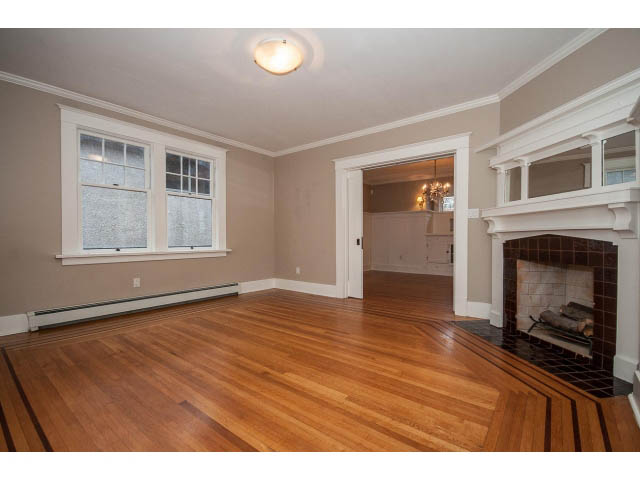 Bright living room with hardwood floors and a fireplace, leading to a dining area. - 769 West 20th Ave, Vancouver West Side
