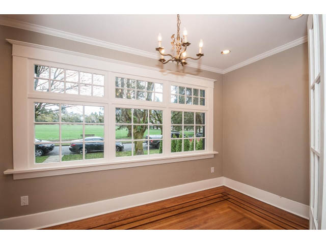 Bright living room with large windows and hardwood floors, showcasing a city view. - 769 West 20th Ave, Vancouver West Side