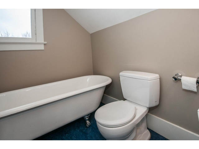 Bathroom with bathtub and toilet, neutral walls, window view. - 769 West 20th Ave, Vancouver West Side