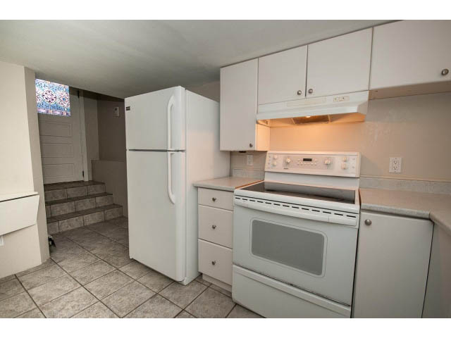 Bright kitchen with white cabinets, tiled floor, and stainless steel appliances. - 769 West 20th Ave, Vancouver West Side