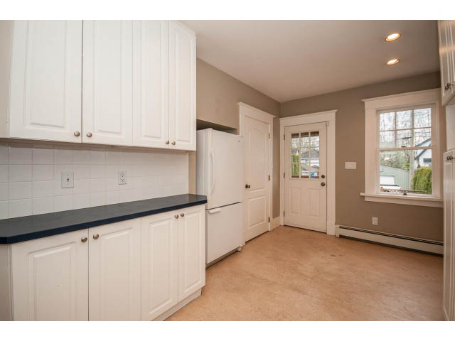 Bright kitchen with white cabinets, black countertops, and hardwood floors. - 769 West 20th Ave, Vancouver West Side