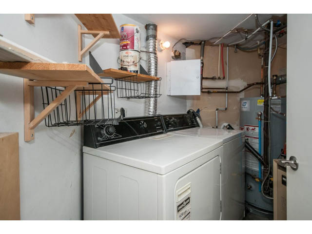 Laundry room with white washer, shelves, and exposed pipes. - 769 West 20th Ave, Vancouver West Side