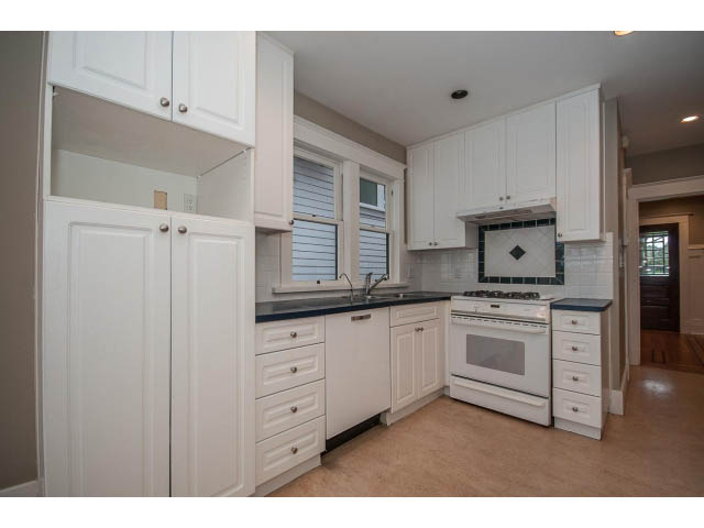 Bright kitchen with white cabinets, granite countertops, and hardwood floors. - 769 West 20th Ave, Vancouver West Side