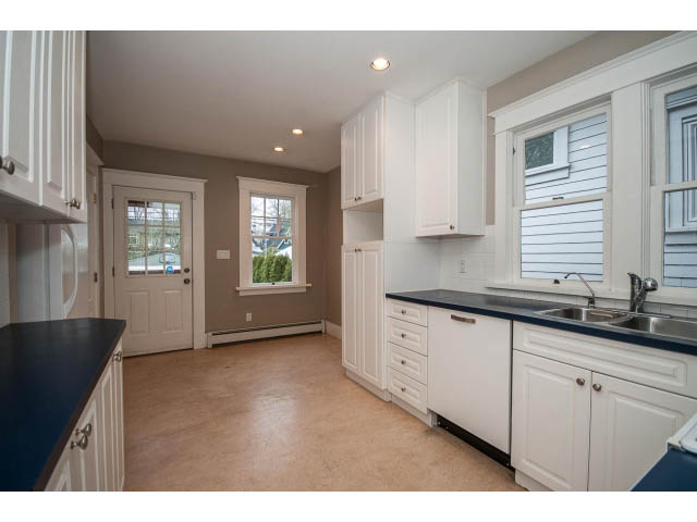 Bright kitchen with white cabinets, dark countertops, and a view of the city. - 769 West 20th Ave, Vancouver West Side