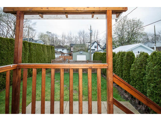 Porch with wooden railing and green hedge backdrop. - 769 West 20th Ave, Vancouver West Side