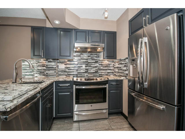 Bright kitchen with stainless steel appliances, granite countertops, and black cabinetry. - 1808 - 1189 Howe St, Vancouver Downtown