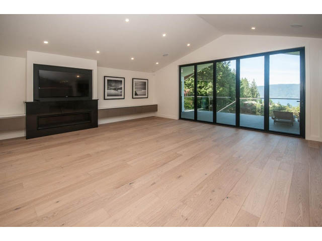Spacious living room with hardwood floors, large windows, and a modern TV setup. - 5235 Headland Dr., West Vancouver