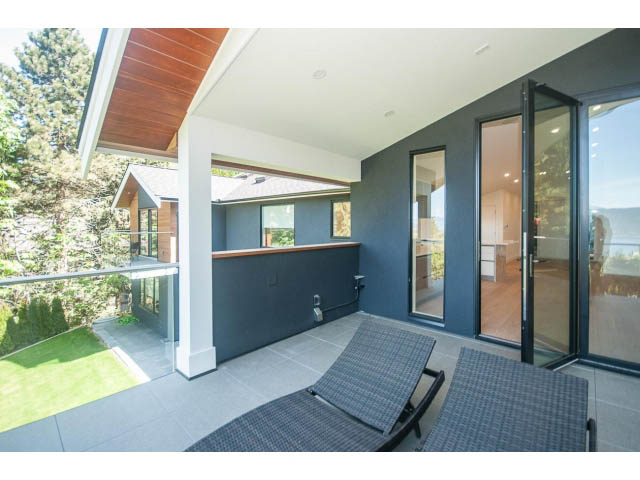 Spacious living room with large windows, modern furniture, and a view of the garden. - 5235 Headland Dr., West Vancouver