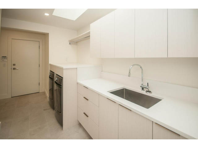 Bright kitchen with white cabinetry and granite countertops, modern sink, and tiled floor. - 5235 Headland Dr., West Vancouver