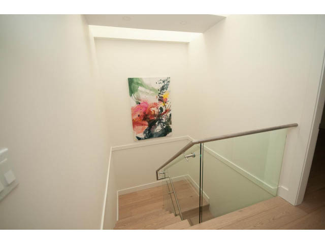 Staircase leading to upper level with colorful abstract art and glass railings. - 5235 Headland Dr., West Vancouver