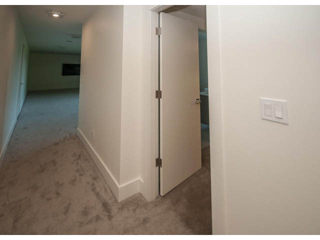 Empty hallway leading to a door, carpeted floor, white walls. - 5235 Headland Dr., West Vancouver