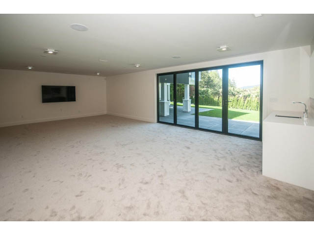 Spacious living room with large windows, natural light, and a flat-screen TV. - 5235 Headland Dr., West Vancouver