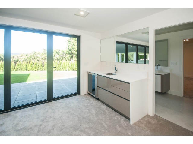 Bright kitchen with modern countertops and large windows offering a view of greenery. - 5235 Headland Dr., West Vancouver