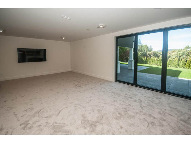 Spacious living room with large sliding doors leading to a garden view. - 5235 Headland Dr., West Vancouver