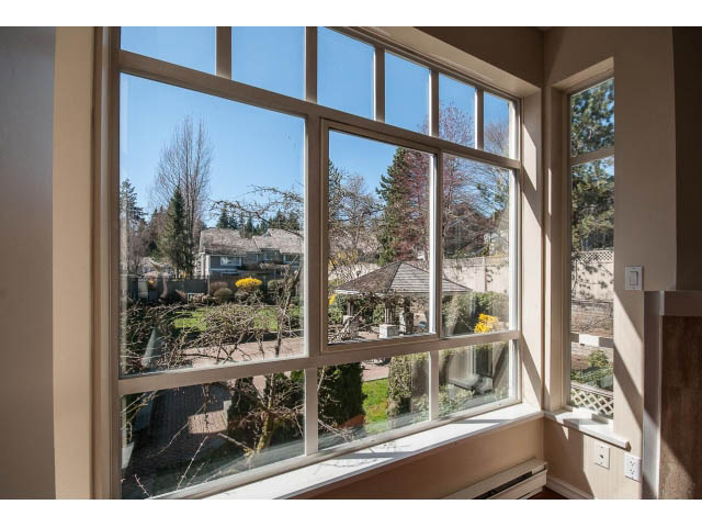 Bright sunroom with expansive windows showcasing a serene garden view. - 204 - 630 Roche Point Drive, North Vancouver