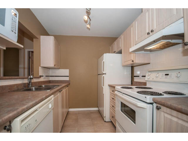 Bright kitchen with granite countertops, white appliances, and light wood cabinets. - 204 - 630 Roche Point Drive, North Vancouver