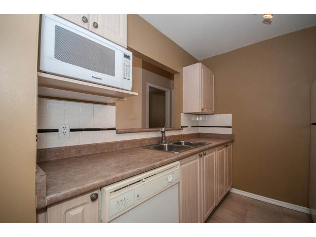 Bright kitchen with granite countertops and wooden cabinets. - 204 - 630 Roche Point Drive, North Vancouver