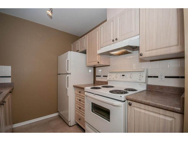 Bright kitchen with white appliances, granite countertops, and light wood cabinets. - 204 - 630 Roche Point Drive, North Vancouver