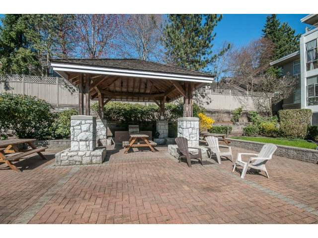 Furnished patio with picnic tables, stone walls, and a covered gazebo. - 204 - 630 Roche Point Drive, North Vancouver