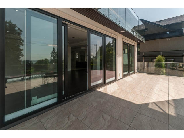 Spacious living room with large glass doors, city view, and modern tile flooring. - 2333 Mathers Ave, West Vancouver