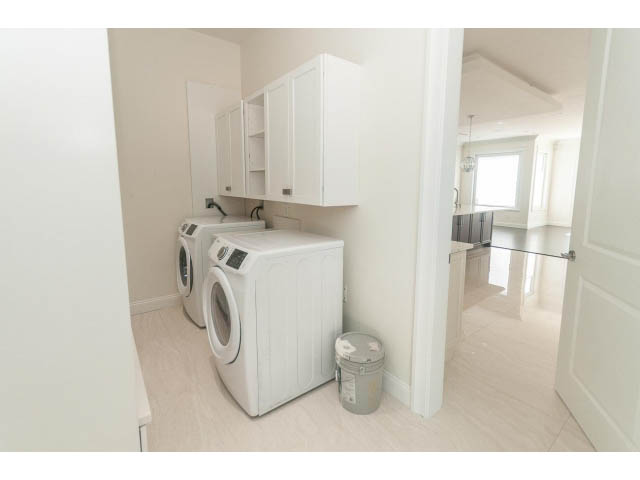 Bright laundry room with white cabinets and modern appliances. - 2333 Mathers Ave, West Vancouver