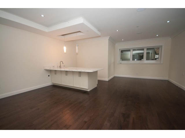 Bright kitchen with white cabinets and hardwood floors, featuring a modern sink and a large window. - 2333 Mathers Ave, West Vancouver