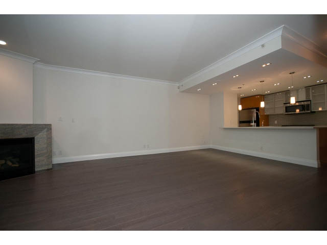 Spacious living room with hardwood floors and modern kitchen in the background. - 21 Smithe Mews, Vancouver Downtown