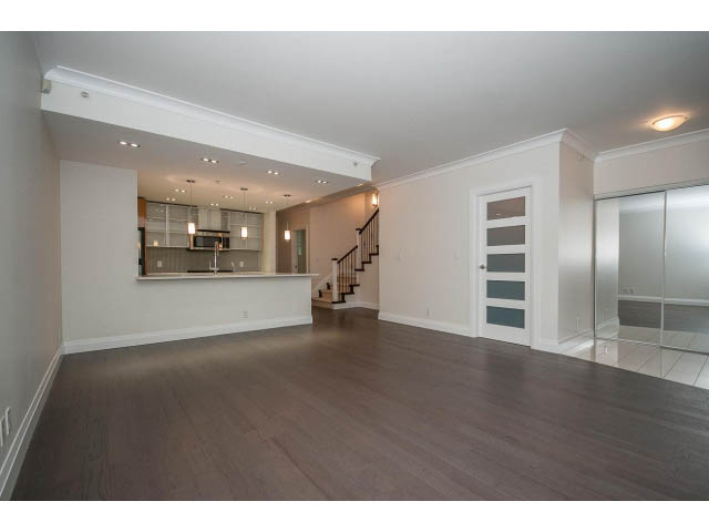 Spacious open-concept living room with hardwood floors and modern kitchen in the background. - 21 Smithe Mews, Vancouver Downtown