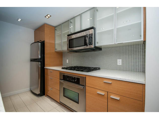 Bright kitchen with modern appliances, light wood cabinets, and white countertops. - 21 Smithe Mews, Vancouver Downtown
