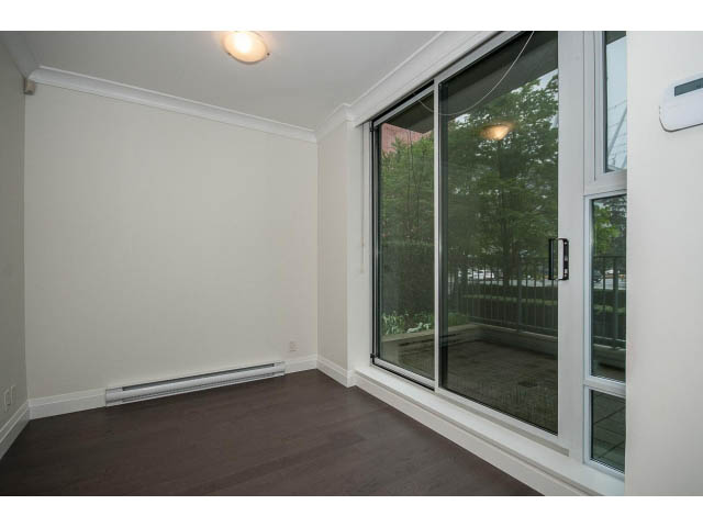 Bright living room with large windows, hardwood floors, and a view of greenery outside. - 21 Smithe Mews, Vancouver Downtown