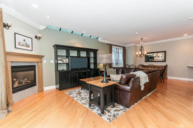 Spacious living room with hardwood floors, a cozy fireplace, and a large entertainment center. - 2031 Creelman Ave, Vancouver West Side