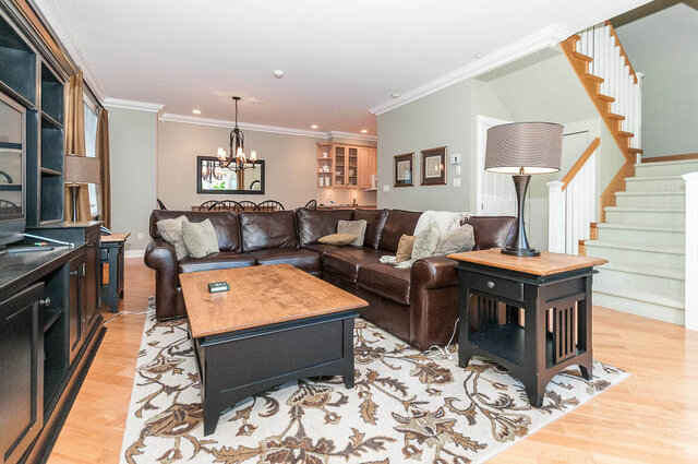 Spacious living room with hardwood floors, a large sectional sofa, and a stylish coffee table. - 2031 Creelman Ave, Vancouver West Side