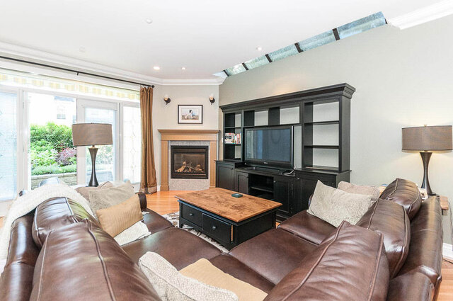 Spacious living room with a fireplace, large TV, and comfortable leather sofas. - 2031 Creelman Ave, Vancouver West Side
