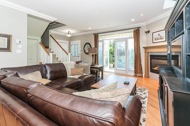 Spacious living room with leather couch, hardwood floors, and a fireplace. - 2031 Creelman Ave, Vancouver West Side