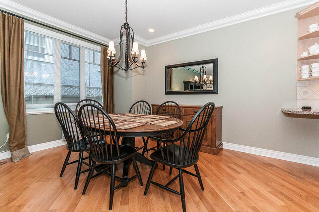 Elegant dining room with hardwood floors, black chairs, and a chandelier, perfect for a cozy meal. - 2031 Creelman Ave, Vancouver West Side