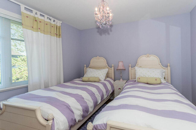 Spacious bedroom with twin beds, lavender walls, and a chandelier, perfect for a cozy stay. - 2031 Creelman Ave, Vancouver West Side