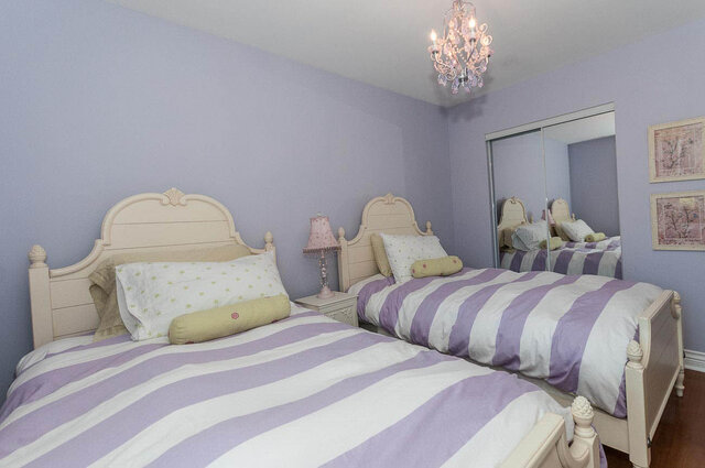 Spacious bedroom with lavender walls, striped bedding, and a chandelier, perfect for a cozy stay. - 2031 Creelman Ave, Vancouver West Side