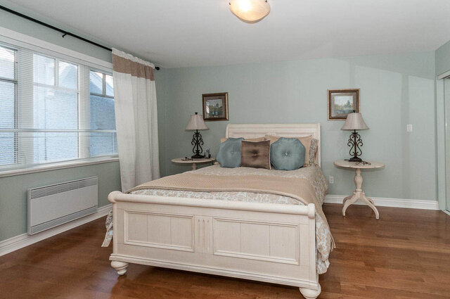 Spacious bedroom with hardwood floors, light blue walls, and a large window with blinds. - 2031 Creelman Ave, Vancouver West Side