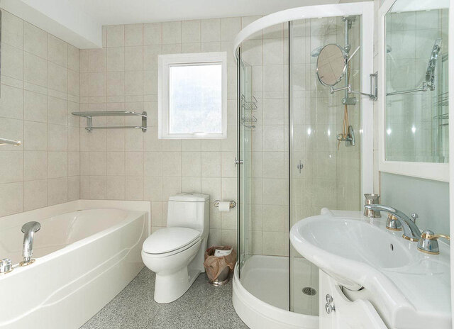Spacious bathroom with a bathtub, toilet, and walk-in shower, featuring a sleek sink and ample counter space. - 2031 Creelman Ave, Vancouver West Side