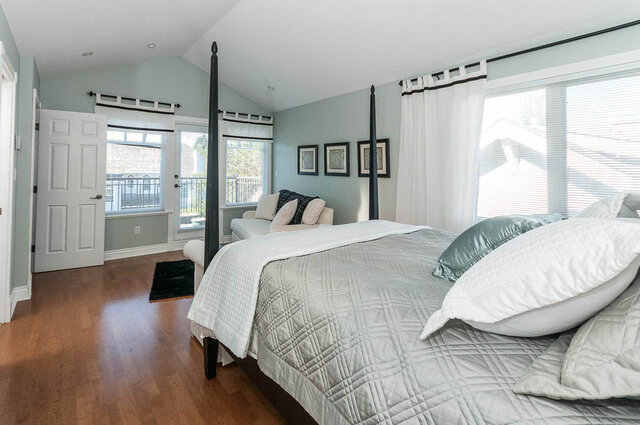 Spacious master bedroom with hardwood floors, a four-poster bed, and a city view. - 2031 Creelman Ave, Vancouver West Side