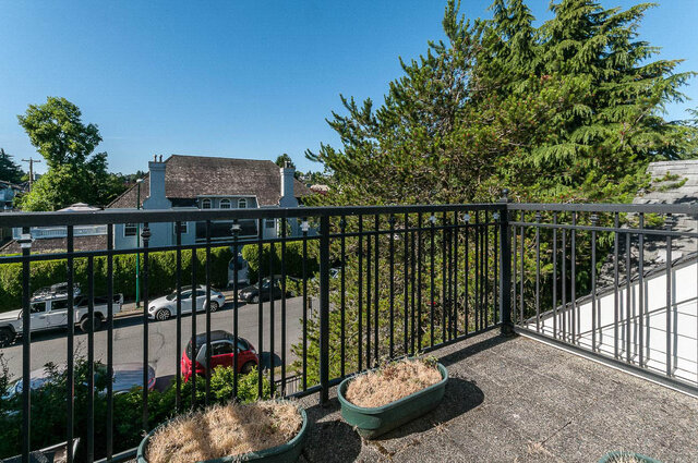 Bright balcony with black railing, potted plants, and a view of neighboring houses and trees. - 2031 Creelman Ave, Vancouver West Side
