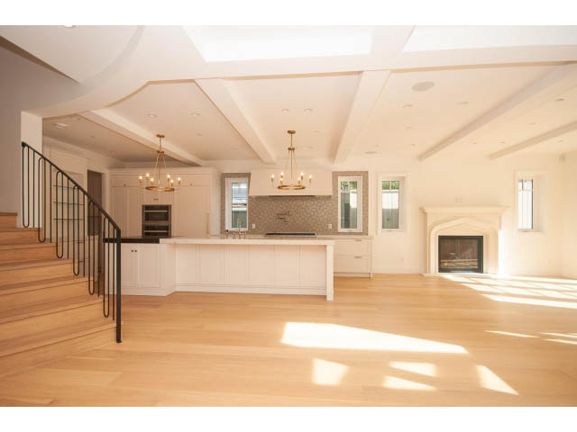 Open-concept living area with hardwood floors, a fireplace, and a chandelier. - 6448 Argyle Ave, West Vancouver