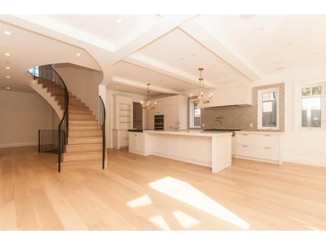 Bright kitchen with white cabinetry, hardwood floors, and a view of the living area. - 6448 Argyle Ave, West Vancouver