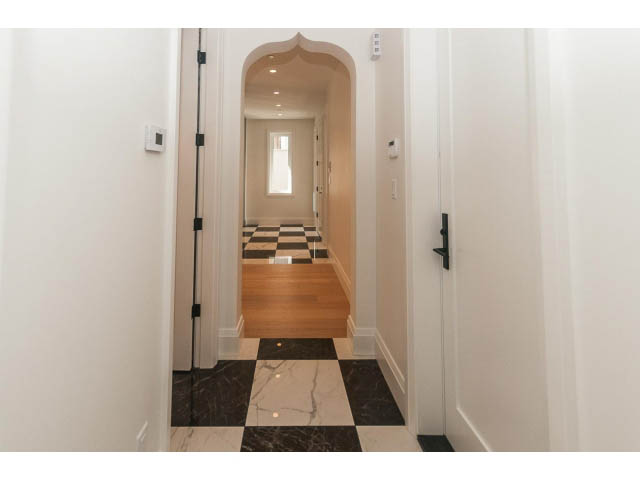 Narrow hallway with checkered floor and arched doorway leading to another room. - 6448 Argyle Ave, West Vancouver