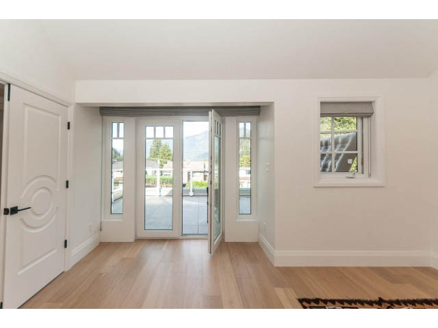 Bright living room with hardwood floors and a view of the mountains. - 6448 Argyle Ave, West Vancouver