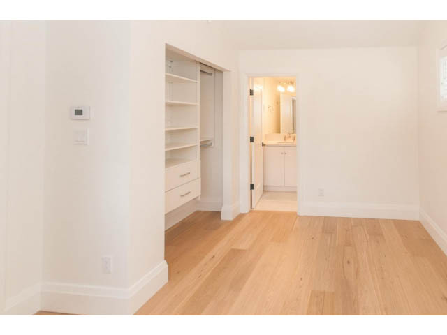 Bright hallway with open shelving and hardwood floors leading to a bathroom. - 6448 Argyle Ave, West Vancouver