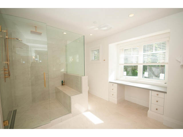 Spacious bathroom with glass shower, white cabinetry, and large windows. - 6448 Argyle Ave, West Vancouver