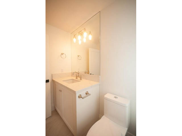 Bright bathroom with white countertops and a toilet, clean and minimalistic. - 6448 Argyle Ave, West Vancouver